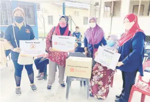  ?? ?? BANTUAN: Siti Aminah (kanan) menyampaik­an ‘Kotak Kasih’ kepada salah seorang penerima dalam satu majlis yang diadakan di Dewan Terbuka KRT Kg Limbawang.