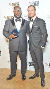  ??  ?? Director Steve McQueen, left, the winner of the BFI Fellowship Award, poses for photograph­ers with presenter Michael Fassbender, in the press room during the London Film Festival Awards, in London. —AP photos