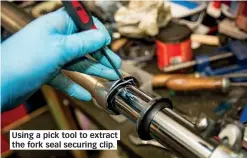  ??  ?? Using a pick tool to extract the fork seal securing clip.