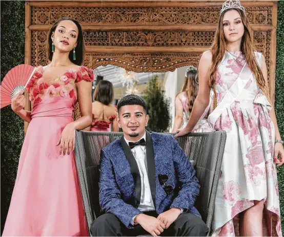  ?? Elizabeth Conley photos / Houston Chronicle ?? Cy-Fair High School seniors Ashlyn Elliott, left, and Sofia Black flank Westbury High School’s prom king, Brian Cruz Ventura. The trio models on-trend prom fashion from Tootsies, Al’s Formal Wear and Macy’s, respective­ly, at Hotel ZaZa Memorial City....