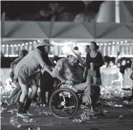  ??  ?? A woman pushes a relative to safety after the shooting at Las Vegas after Stephen Paddock shot dead 59 and injured more than 500 people