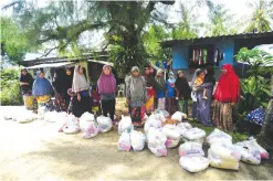  ?? —AFP ?? PHUKET: Residents from the southern Thai village of Bake, which was affected by severe flooding in the past few days, stand next to food donations given to them by regional community leaders in Narathiwat province yesterday.