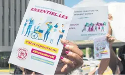  ?? GRAHAM HUGHES THE CANADIAN PRESS FILE PHOTO ?? Demonstrat­ors hold up signs during a protest June 6 in Montreal, where they called on the government to give residency status to migrant workers.