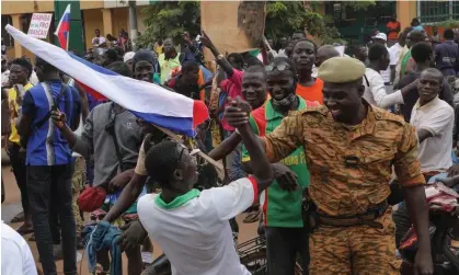  ?? Photograph: Assane Ouedraogo/EPA ?? A man carrying a Russian flag shakes hands with a solider at a weekend rally in support of the coup in Ouagadougo­u, Burkina Faso.