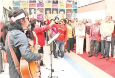  ??  ?? (From left) Madius, Juhar and Yusof watching a performanc­e at the Upko Christmas open house celebratio­n in Likas.