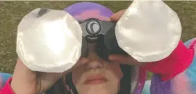  ?? ELLIOT FERGUSON ?? Aubrey Elliott, 9, looks through a modified set of binoculars during the solar eclipse in Kingston on Monday.