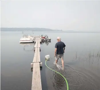  ?? DARRYL DYCK/THE CANADIAN PRESS ?? Jack Keough is using a generator to draw water from Green Lake to protect his property from a wildfire. Since April 1, there have been 1,029 fires in B.C., and 149 are still burning.