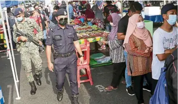  ?? — IZZRAFIQ ALIAS/The Star ?? Food market: Lance Corporal Jack Jopinu with a soldier inspecting a Ramadan bazaar at Jalan Teluk Pulai in Klang.