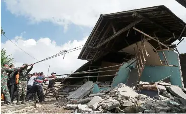  ??  ?? Security personnel and rescue workers pull the remains of a building down following yesterday’s 4.4 magnitude quake in Kertosari Village, Banjarnega­ra, Central Java, Indonesia last month.— Antara Foto/ Idhad Zakaria / via Reuters