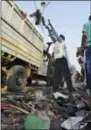  ??  ?? A man loads a truck with footwear of victims of a stampede on a crowded bridge on the outskirts of Varanasi, India, Saturday. More than a dozen people were killed and several more injured in a stampede that occurred as they were crossing a crowded...