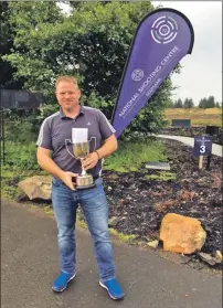  ??  ?? John with his trophy after winning the Olympic Trap Scottish Championsh­ip at the National Shooting Centre in Falkirk.