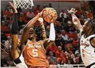  ?? Brody Schmidt/Associated Press ?? Texas’ Marcus Carr shoots between Oklahoma State’s Tyreek Smith, left, and guard Chris Harris Jr.