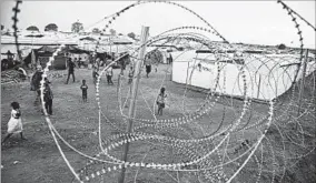  ?? AP ?? Displaced South Sudanese walk at the camp in Wau. More than 200,000 people still shelter in the camps.