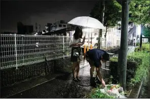  ?? AP/JAE C. HONG ?? A couple places flowers today near a cordoned-off animation studio in Kyoto, Japan, where 33 people perished in a fire Thursday.