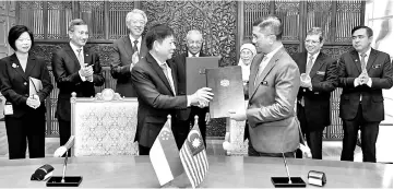  ??  ?? Azmin (centre) exchanges the agreement documents with Khaw, witnessed by Dr Mahathir (middle),Wan Azizah (back, third from right), Teo (back, third from left) and other ministers yesterday.