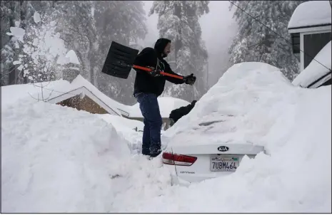  ?? JAE C. HONG — THE ASSOCIATED PRESS ?? Kenny Rybak, 31, shovels snow around his car in Running Springs, Calif., on Tuesday. Beleaguere­d California­ns got hit again Tuesday as a new winter storm moved into the already drenched and snow-plastered state, with blizzard warnings blanketing the Sierra Nevada and forecaster­s warning residents that any travel was dangerous.