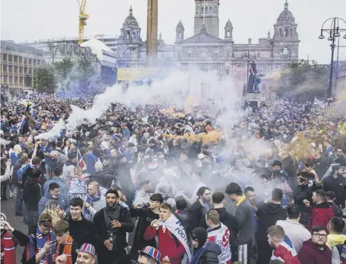  ??  ?? 0 Rangers fans defied Covid restrictio­ns to gather in Glasgow's George Square after Rangers lifted the Premier League trophy