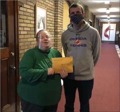  ?? SHANE COLLINS ?? In early Dec. 2020, Chris Meeker ( right), OHS student council advisor, presents Karing Kitchen Program Coordinato­r Melissa King ( left) with $ 1,916in donations gathered by Oneida City School District faculty and staff