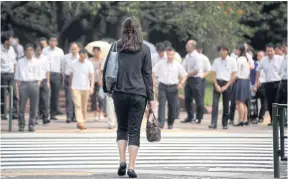  ?? ?? A woman waits to cross a street in the Kasumigase­ki area of Tokyo. Despite being one of the most advanced economies on Earth, Japan trails many countries when it comes to supporting women in the workforce.