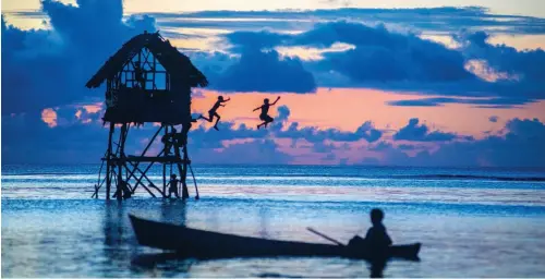  ??  ?? Opening image: Boy in dug out canoe.
Below: Children jumping into the lagoon against the backdrop of a stunning sunset.
Clockwise from top right: Remote resort, photo by Franco Banfi; Skull Island; and lobster salad dinner at Fatboys Resort, Gizo,...