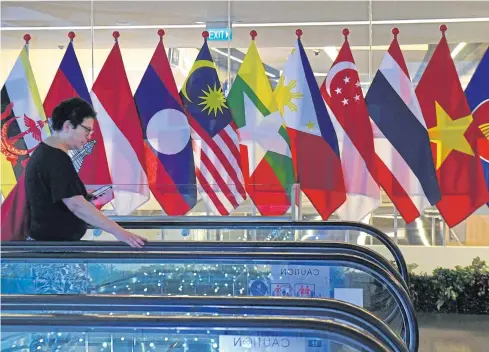  ?? AFP ?? A woman walks past the national flags of Asean countries at the Suntec City convention and exhibition centre in Singapore earlier this month.