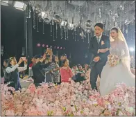  ??  ?? Chen and groom Dou Di walk down the stage during their unmasked wedding banquet.