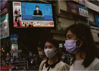  ?? Anthony Kwan / Getty Images ?? Hong Kong residents pass a broadcast of John Lee, the territory’s former No. 2 official, discussing his race to be chief executive. Lee is seen by many as Beijing’s preferred candidate.