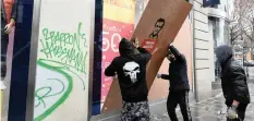  ?? | Reuters ?? WORKMEN place a wooden panel to protect a broken window on a clothing store the day after clashes during a national day of protest in Paris yesterday.