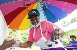  ?? Emily Matthews/Post-Gazette ?? Sandra Bundt Simmons, owner of Sandy’s Boo Delights, hands out a cup of free Italian ice Saturday during a celebratio­n to recognize 50 years of Operation Better Block at Westinghou­se Park in Point Breeze.