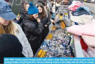  ?? ?? NEW YORK: Tourists browse through vendor stalls along a street after they were forced to move from the )YVVRS`U )YPKNL VU [OL ÄYZ[ KH` [OH[ H UL^ SH^ V\[SH^PUN ]LUKVYZ VU [OL IYPKNL ^LU[ PU[V LMMLJ[ VU 1HU\HY` 03, 2024 in New York City. The new law is designed to clear the heavily packed pedestrian walkway on the bridge, one of Manhattan’s top tourist attraction­s. — AFP