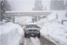  ?? AP PHOTO/JAE C. HONG ?? A truck drives along snow berms Feb. 28 in Running Springs, Calif.