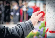  ?? FRANK GOGOS ?? A poppy is added to a cross on Remembranc­e Day.