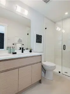  ??  ?? Bathrooms feature wood grain, flat-panel cabinets with soft-close doors.