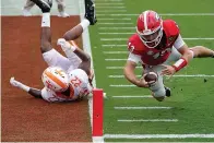  ?? AP Photo/John Bazemore ?? ■ Georgia quarterbac­k Stetson Bennett (13) dives past Tennessee defensive back Jaylen McCollough (22) to score a touchdown in the first half of an NCAA college football game Saturday in Athens, Ga.