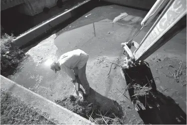  ?? Staff photo by Evan Lewis ?? Ray Stuard, a laborer with TexAmerica­s, fills the bucket of a backhoe June 29, 2016. The TexAmerica­s crew was cleaning out a drainage culvert near the entrance to one of its tenants.