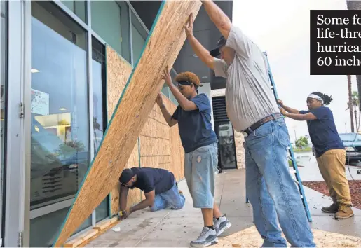  ?? COURTNEY SACCO ?? Crews board up windows at the La Palmera Mall in Corpus Christi on Friday as Hurricane Harvey approaches.