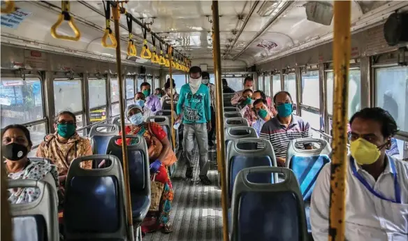  ??  ?? Bus passengers in South East Asia practising social distancing while wearing face-masks as a health precaution.