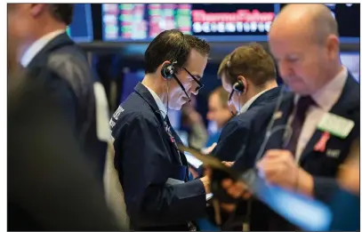  ?? (AP/Alyssa Ringler) ?? Gregory Rowe (center) works Thursday on the trading floor in this photo supplied by the New York Stock Exchange. Stocks posted solid gains Thursday, rising on optimism among investors on the condition of the global economy.