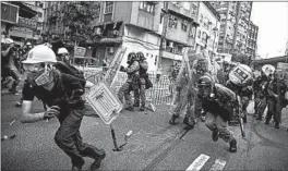  ?? ERIC TSANG/HK01 ?? A masked protester runs from police officers during a protest Saturday in Hong Kong.