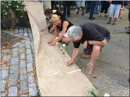  ?? EVAN BRANDT — MEDIANEWS GROUP ?? John Kennedy, right, joins Twila Fisher and Cathy Skitko in writing messages about violence on a banner listing 2019 shootings. Kennedy said his message was “no more war weapons for citizens. Do something!”