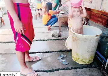  ??  ?? IMPROVISED BATH TUB – A young boy beats the summer heat by submerging himself in an improvised swimming tub and pouring water over his head along an alley in an informal settlers’ community in Davao City. (Keith Bacongco)