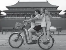  ?? ALESSANDRO BIANCHI/REUTERS ?? A family rides a bicycle past a palace in the Forbidden City in Beijing just prior to the 2008 Summer Olympic Games.