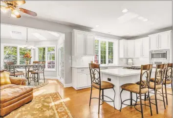  ??  ?? The newly renovated kitchen is dressed in white Shaker- style cabinetry, marble backsplash, quartz counters, stainless steel appliances, island with bar seating and walk- in pantry.