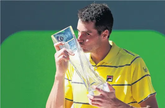  ?? PHOTO: USA TODA ?? American John Isner kisses the Butch Buchholz championsh­ip trophy after beating German Alexander Zverev 67(47), 64, 64 in the men’s singles final at the Miami Open yesterday.