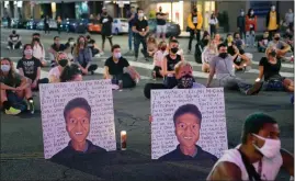  ?? The Associated Press ?? Two people hold posters showing images depicting Elijah McClain during a candleligh­t vigil for McClain outside the Laugh Factory in Los Angeles in August 2020.
