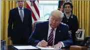  ?? EVAN VUCCI — THE ASSOCIATED PRESS ?? President Donald Trump signs a coronaviru­s aid package to direct funds to small businesses, hospitals and testing.