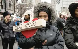  ??  ?? Tiawanna Green carries the cross for her godbrother, Brian Fields, during a peace march down the Magnificen­t Mile on Dec. 31, 2016.
| ASHLEE REZIN/ SUN- TIMES