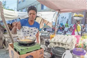  ??  ?? Phita, 36, a vendor who did not give her last name, prepares an omelet sandwich at the Salomon market in Haiti’s capital, Port-au-Prince. Most market vendors use eggs brought in illegally from the Dominican Republic because domestic eggs are too...