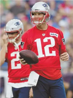  ?? STAFF PHOTO BY FAITH NINIVAGGI ?? ALL SMILES: Patriots quarterbac­k Tom Brady warms up in front of backup Brian Hoyer during last night’s training camp workout at Gillette Stadium in Foxboro.