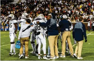  ?? DANNY KARNIK / GEORGIA TECH ATHLETICS ?? Georgia Tech character developmen­t coach Derrick Moore (holding baton) huddles with a special-teams unit before it takes the field in a 27-21 win over Miami last Saturday.